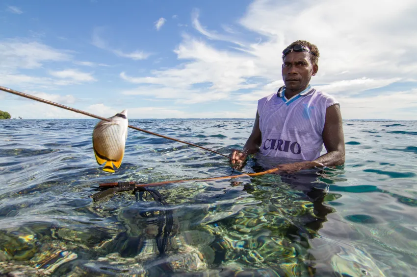 a spear fisher with a speared tropical fish