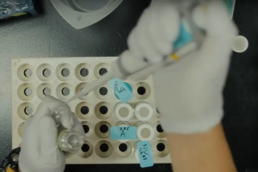 Screenshot from video showing hands of researcher wearing gloves and pipetting.