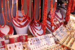 a display case of red coral jewelry containing necklaces, earrings, bracelets, and rings