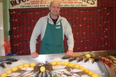 Man standing with an array of fresh seafood for sale.