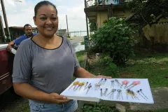 Una mujer sostiene una bandeja blanca que exhibe joyas de pez león.