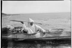 a hunter throws a harpoon from the cockpit of his kayak