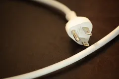 a white power cord unplugged on a brown table