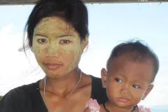 a Malaysian woman with paste on her face and a baby in her arms