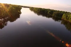 An aerial shot of a tree-lined section of the Mississippi River at sunset. 