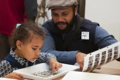 An adult and child visitor participate in an activity at the Natural History Museum 