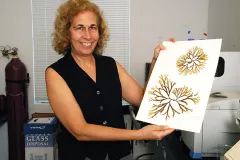a woman holding up algal specimens