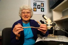 a woman at a desk holding a worm
