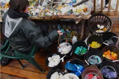 A volunteer sorts washed plastic collected from the beach into buckets by color and size. 