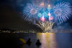 Colorful fireworks go off over the water.
