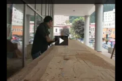 A screenshot from the video of a carver using traditional tools to shape a canoe. 
