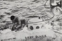 a man sits atop a submersible at the sea surface