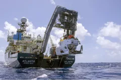 a white sub hangs off an A frame off the back deck of a ship