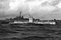 a submersible surfaces next to a ship