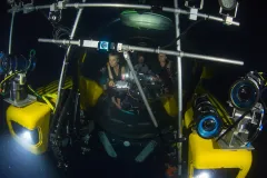 three people sit in a yellow submersible