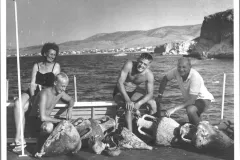 a mother, father and their two adult sons sit with scuba gear on a ship