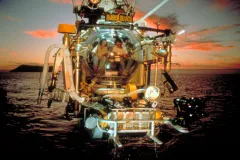 a submersible is lowered into the ocean during sunset