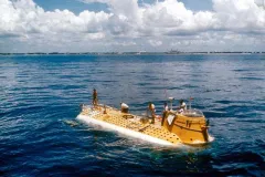a yellow submarine at sea level with men standing on top