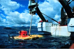 a yellow and orange submarine off the back deck of a research vessel