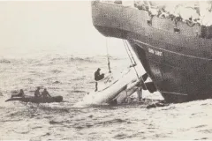 a submersible hangs from a cable over the edge of a large ship