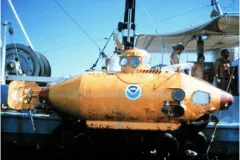A yellow submarine suspends next to a research vessel