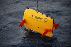 a yellow ROV hangs above the ocean