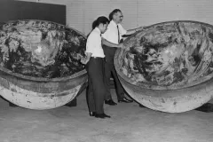 two men stand next to two giant halve spheres