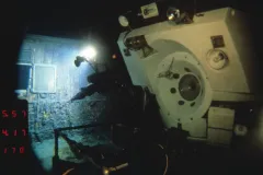 a white submersible shines a light on a ship wreck