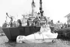 a small white submersible sits next to a research vessel