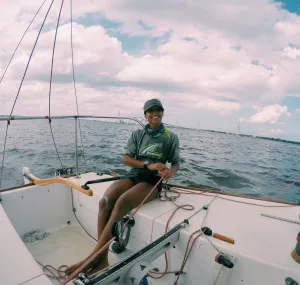 Hannah steering a sailboat on the water. 