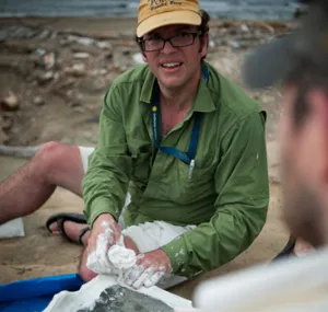 Jorge Velez-Juarbe sitting on sand while working on a dig.