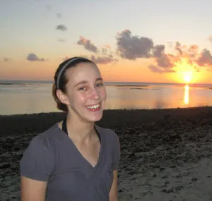 Christine Hoekenga smiling at the camera with sunset on the beach behind her. 