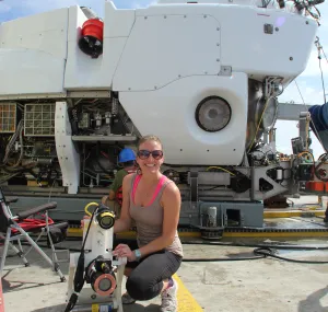 Caroline Johansen kneels in front of an ROV with some oceanography equipment. 