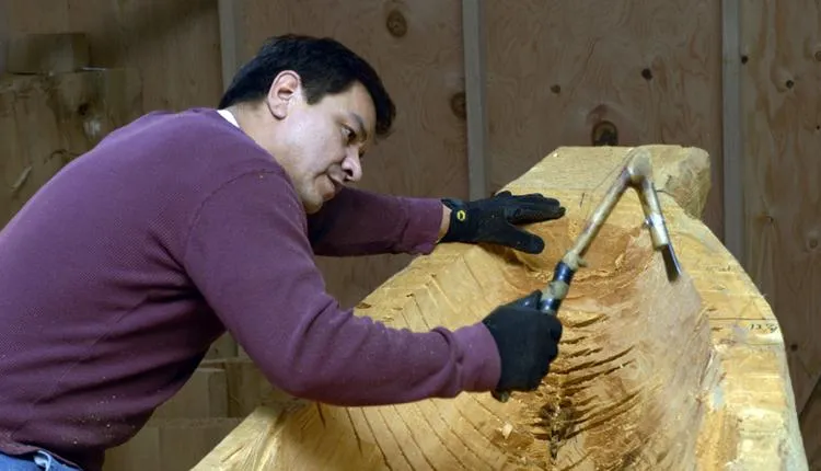 Douglas Chilton uses traditional carving tools to shape the Raven Spirit canoe.