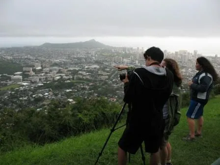 Students studying rainfall point their camera to the clouds.