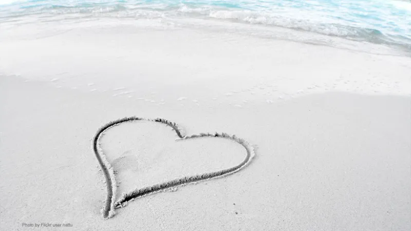 A photo of a beach with a heart inscribed in the sand. 