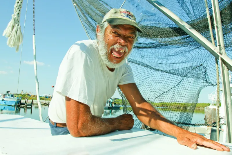 A Gulf Coast resident sits on his boat, smiling for the camera.