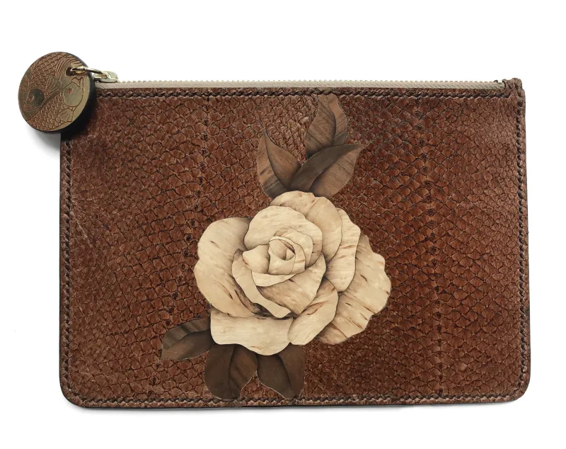 A brown clutch bag made from fish skin with a beige flower in the center, patterned with wood grain.