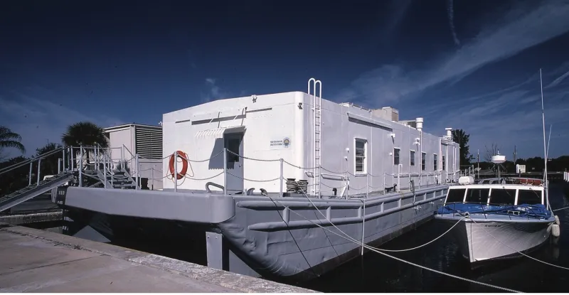 A small ship with a building on it  