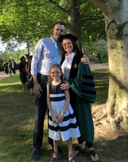 a young family of three celebrate the mother's graduation