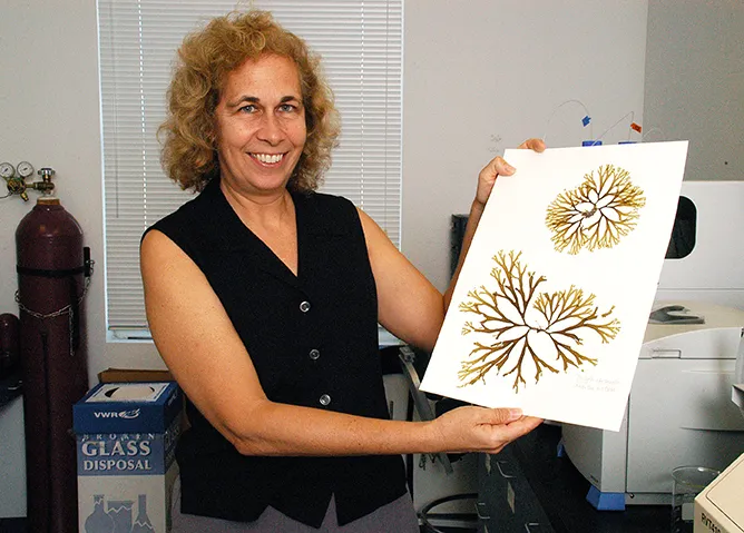 a woman holding up algal specimens