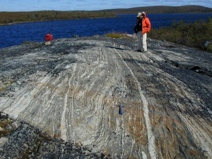 a person stands on a rock ledge and looks at the striations in the rock