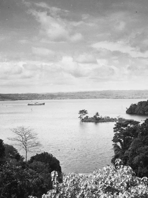 a lake with a ship and some nearby hills with trees