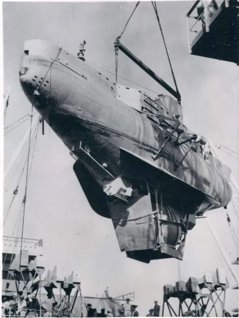 a large submarine hangs from a crane