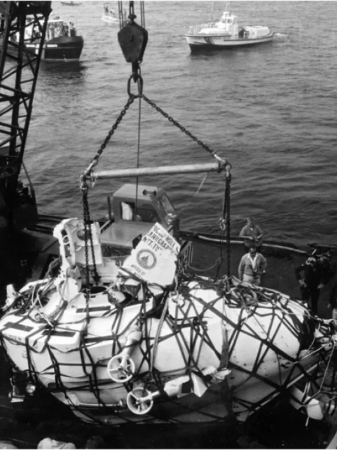 a submarine is lifted in a large net at the ocean's surface